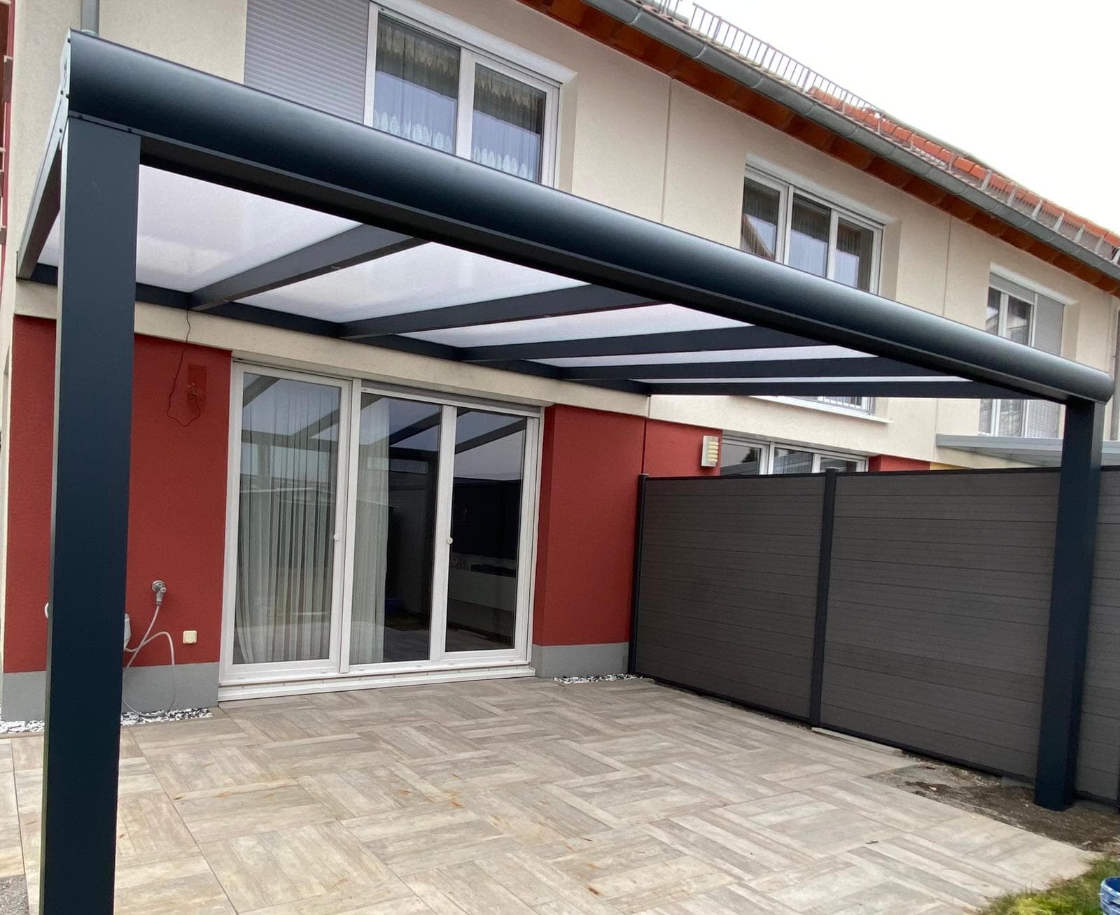 Terrassenüberdachung aus Stahl in Anthrazit mit lichtdurchlässiger Eindeckung, an ein Reihenhaus angebaut